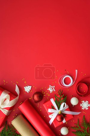 Téléchargez les photos : Noël Cadeau boîte et décorations à fond rouge. Emballage cadeau de Noël. Vertical. - en image libre de droit