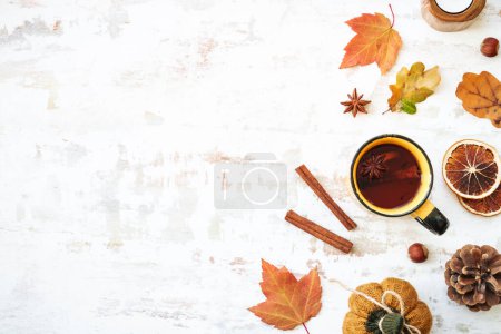 Foto de Fondo de caída. Acogedor otoño en blanco. Taza de té picante, hojas de otoño, especias y decoración. Piso con espacio de copia. - Imagen libre de derechos