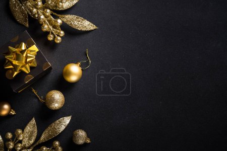 Téléchargez les photos : Décorations en or de Noël et boîte cadeau sur noir. Image de pose plate avec espace de copie. - en image libre de droit