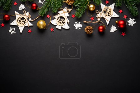 Foto de Árbol de Navidad con decoraciones navideñas en fondo negro. Decoraciones de juguete de madera. Piso con espacio de copia. - Imagen libre de derechos