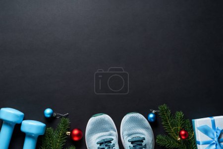 Foto de Christmas fitness y concepto de estilo de vida saludable. Decoraciones navideñas y equipamiento deportivo en fondo negro. Piso con espacio de copia. - Imagen libre de derechos