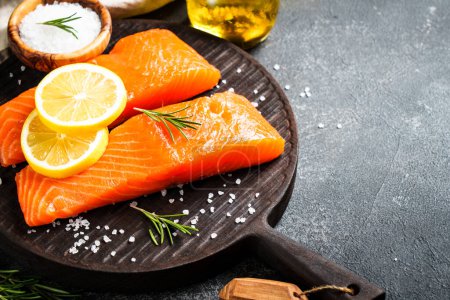 Photo for Salmon fillet with lemon and spices. Raw fish at craft cutting board.. - Royalty Free Image
