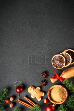 Téléchargez les photos : Biscuits au pain d'épice, épices et décorations de Noël au noir. Vue du dessus avec espace pour le texte. - en image libre de droit