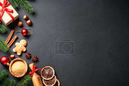Téléchargez les photos : Nourriture de Noël et ingrédients pour cuisiner au noir. Biscuits au pain d'épice, épices et décorations de Noël. Pose plate avec espace pour le texte. - en image libre de droit