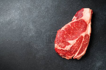 Téléchargez les photos : Un steak de boeuf. Ribeye steak viande crue sur noir. Vue supérieure avec espace de copie. - en image libre de droit