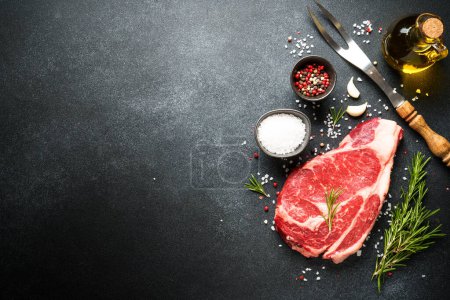 Photo for Beef steak with spices on black background. Ribeye steak raw meat. Top view with copy space. - Royalty Free Image