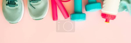 Foto de Equipo de fitness sobre fondo rosa, imagen plana. Zapatillas, mancuernas, toalla y botella de agua. Formato de banner largo. - Imagen libre de derechos