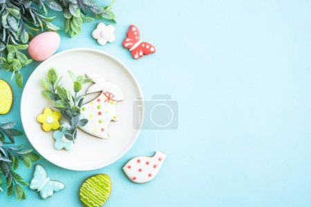 Téléchargez les photos : Fond alimentaire de Pâques. Assiette blanche avec œufs, fleurs de printemps et biscuits de Pâques. Pose plate. - en image libre de droit