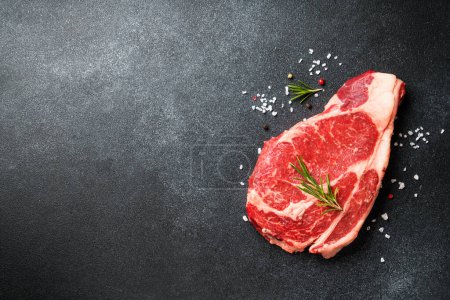 Téléchargez les photos : Un steak de boeuf. Ribeye steak viande crue sur noir. Vue supérieure avec espace de copie. - en image libre de droit
