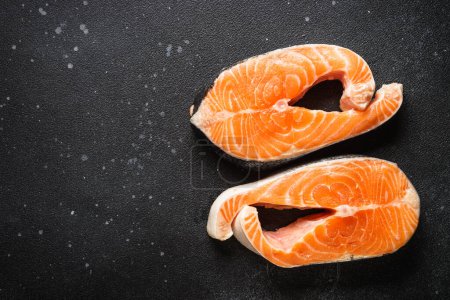 Photo for Raw fish, fresh salmon steaks at black background. - Royalty Free Image