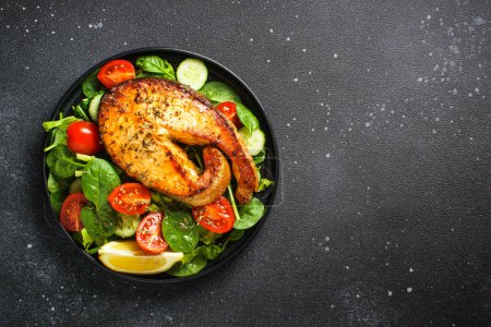 Foto de Ensalada de salmón con filete fresco y verduras sobre fondo negro. Dieta Keto, comida saludable. Espacio de copia vista superior. - Imagen libre de derechos