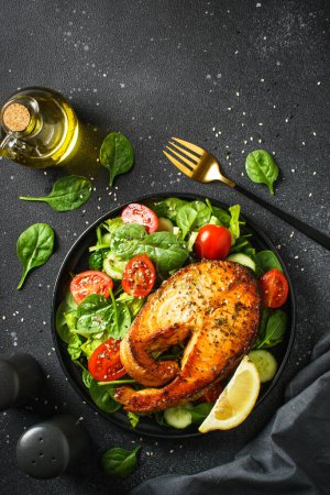 Foto de Filete de salmón y ensalada verde fresca sobre fondo negro. Dieta Keto, comida saludable. Dieta mediterránea. - Imagen libre de derechos