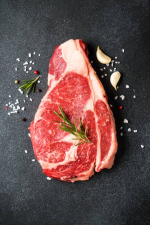 Photo for Beef steak. Ribeye steak raw meat on black. Top view with copy space. - Royalty Free Image