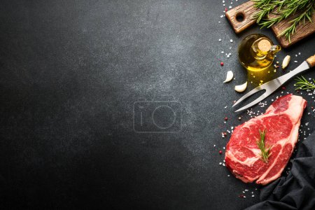 Foto de Filete de carne cruda con especias sobre fondo negro. Filete de res ribeye. Vista superior con espacio de copia. - Imagen libre de derechos