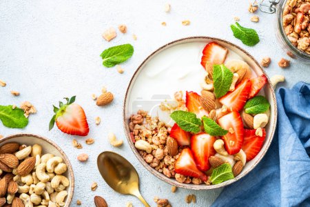 Photo for Yogurt with granola, nuts and strawberries on white. Healthy snack or breakfast, fruit salad. Top view with copy space. - Royalty Free Image