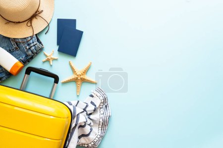 Téléchargez les photos : Voyage fond, vacances d'été. Valise, passeports, chapeau et tissu d'été sur fond bleu. Image de pose plate avec espace de copie. - en image libre de droit