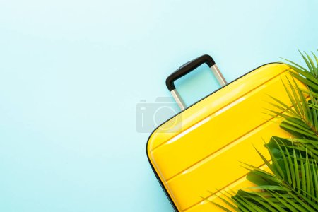 Foto de Vacaciones de verano sobre fondo azul. Maleta amarilla y hojas de palma. Asiento plano con espacio para texto. - Imagen libre de derechos