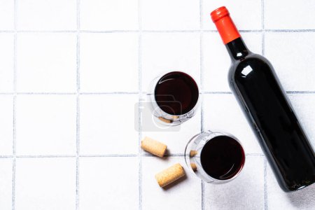 Foto de Vino tinto sobre fondo blanco. Dos vasos con vino, botella de vino y sacacorchos con sombras duras. - Imagen libre de derechos