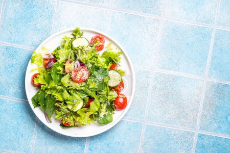Foto de Ensalada de verduras verdes con hojas frescas en plato blanco. Comida saludable, menú dietético. Vista superior con espacio para texto. - Imagen libre de derechos