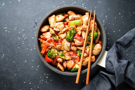Photo for Chicken stir fry with vegetables and sesame at black background. Traditional asian cuisine. - Royalty Free Image