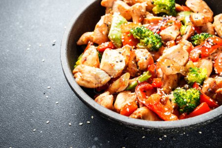 Téléchargez les photos : Remuer le poulet et les légumes et le sésame dans le wok. Cuisine asiatique. Gros plan. - en image libre de droit