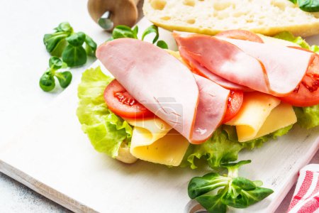 Téléchargez les photos : Sandwich à la laitue, fromage, tomates et jambon. Restauration rapide saine ou collation. Gros plan. - en image libre de droit