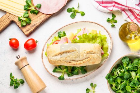 Foto de Sandwich de Ciabatta con lechuga, queso, tomate y jamón. Comida rápida, merienda o almuerzo. Vista superior en blanco. - Imagen libre de derechos