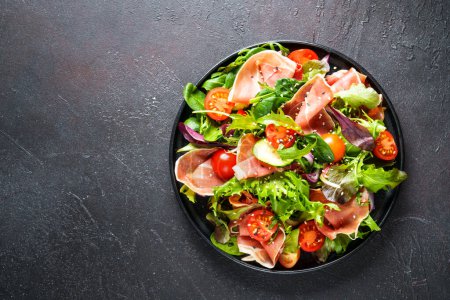 Photo for Healthy food. Fresh salad with jamon, green salad leaves and tomatoes. Top view with space for text. - Royalty Free Image