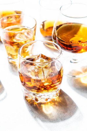 Téléchargez les photos : Forte boisson alcoolisée dans différents verres à fond blanc. - en image libre de droit