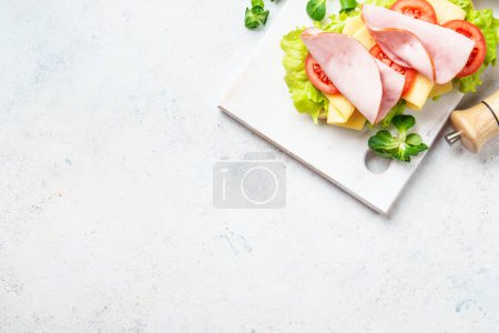 Foto de Sandwich con lechuga, queso, tomate y jamón. Comida rápida saludable o merienda. Vista superior en blanco. - Imagen libre de derechos