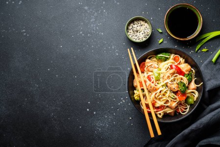Téléchargez les photos : Nouilles asiatiques avec poulet et légumes sur fond noir. Vue de dessus avec espace pour le design. - en image libre de droit