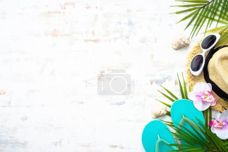 Photo for Summer vacation and travel concept. Palm leaves, hat, flip flop and shells on white background. Flat lay with copy space. - Royalty Free Image