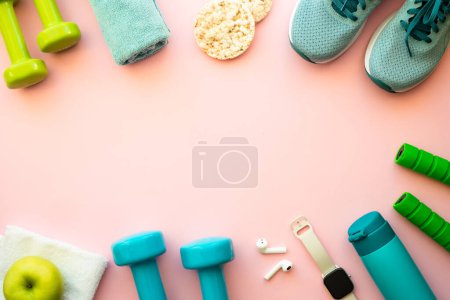 Photo for Healthy lifestyle and fitness concept. Sneakers, dumbbells, towel, green apple and fitness bracelet. Flat lay on pink. - Royalty Free Image