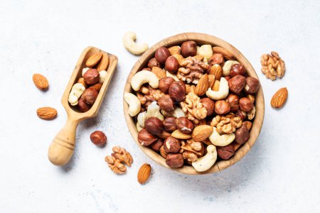Photo for Nuts assortment at white background. Almond, hazelnut, cashew in wooden bowl. Top view - Royalty Free Image