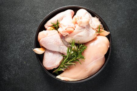 Photo for Raw Chicken with herbs and spices. Different part of chicken - fillet, wings, drumsticks on black. - Royalty Free Image