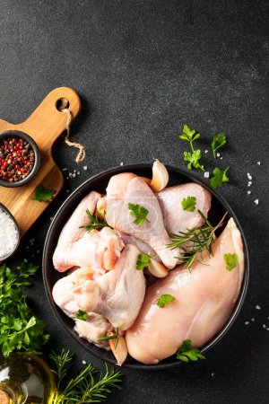 Photo for Raw Chicken with herbs and spices. Different part of chicken - fillet, wings, drumsticks. Flat lay on black background. - Royalty Free Image