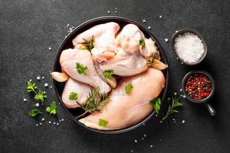 Photo for Chicken wings, drumsticks and breast with herbs and spices on black background. Top view with copy space. - Royalty Free Image