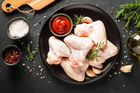 Photo for Chicken wing, raw chicken meat with herbs. Top view on black table. - Royalty Free Image