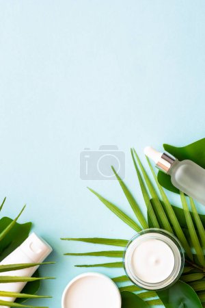 Photo for Summer cosmetic, set of cosmetic products with palm leaves on blue. Top view with copy space. - Royalty Free Image