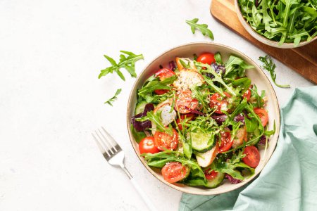 Foto de Ensalada verde con pechuga de pollo al horno, hojas frescas de ensalada y verduras. Vista superior sobre fondo blanco. - Imagen libre de derechos
