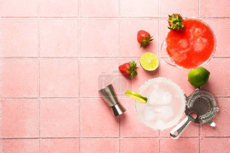 Téléchargez les photos : Margaritas classiques aux fraises avec tequila et citron vert à l'arrière-plan. Vue de dessus sur carrelage rose. - en image libre de droit