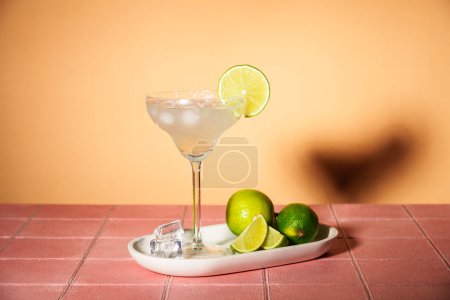 Foto de Margarita, cóctel alcohólico con lima, tequila de plata, cubitos de hielo y sal en vaso alto. Fondo rosa de moda. - Imagen libre de derechos