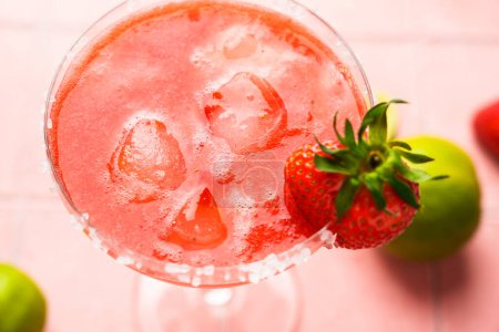 Téléchargez les photos : Margarita aux fraises avec tequila, glace, fraise et citron vert sur fond rose. Gros plan. - en image libre de droit