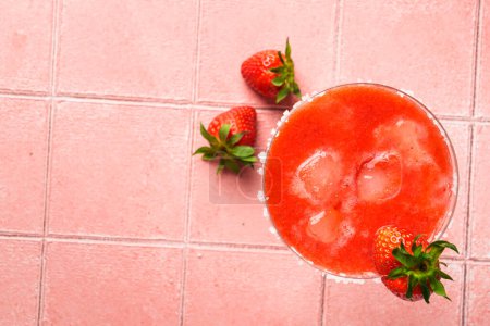 Téléchargez les photos : Margarita aux fraises avec tequila, glace, fraise et citron vert sur fond rose. Image de pose plate avec espace de copie. - en image libre de droit