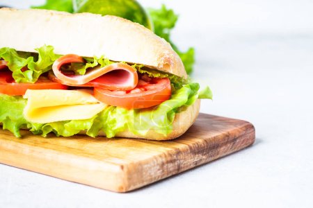 Téléchargez les photos : Sandwich à la ciabatta avec laitue, fromage, tomates et jambon. Snack santé fast food. Isolé sur blanc. - en image libre de droit