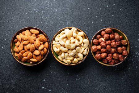 Photo for Nuts assortment in bowls at black background. Flat lay with space for text. - Royalty Free Image