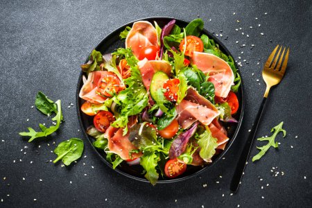 Téléchargez les photos : Une nourriture saine. Salade fraîche avec confiture, feuilles de salade vertes et tomates. Vue du dessus avec espace pour le texte. - en image libre de droit
