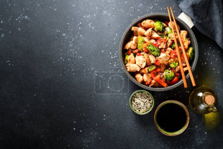 Foto de Pollo salteado con salsa de soja y verduras en el fondo negro. Piso con espacio de copia. - Imagen libre de derechos