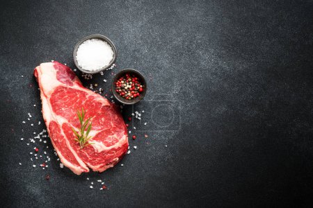 Téléchargez les photos : Un steak de boeuf. Ribeye viande crue de steak vieilli sec sur noir. Vue supérieure avec espace de copie. - en image libre de droit