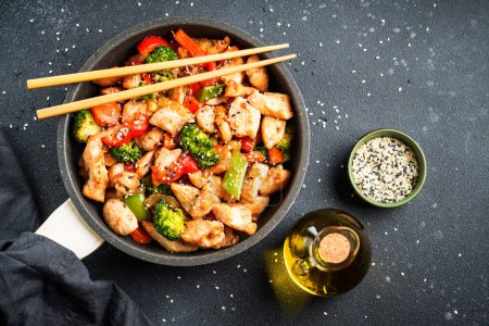 Photo for Stir fry chicken and vegetables and sesame at black background. Asian cuisine. Top view with space for design. - Royalty Free Image